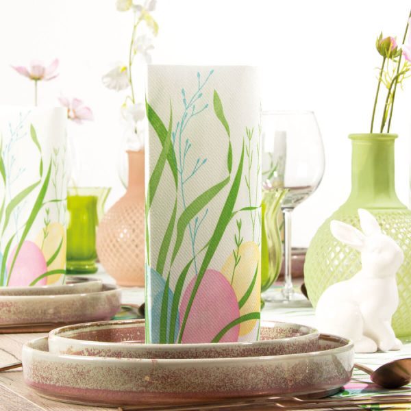 Mank Airlaid Serviette Ostern, dekorativ gefaltet auf einem österlich gedeckten Tisch mit Eiern und Frühlingsblumen